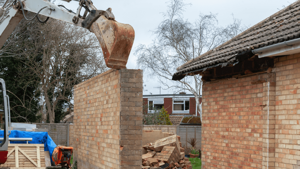 Crane knocking down a single brick wall